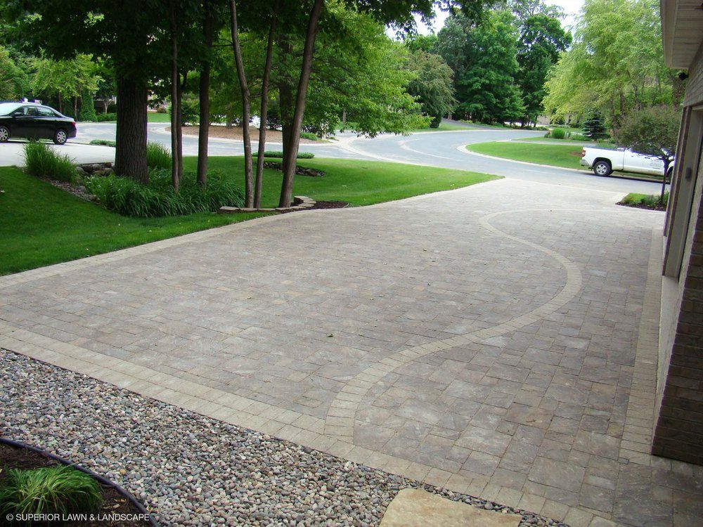 A white car is parked in a driveway next to trees