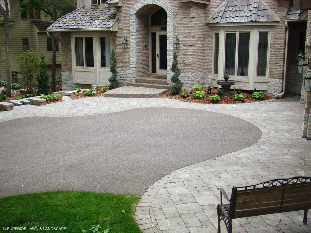 A large house with a curved driveway and a bench in front of it