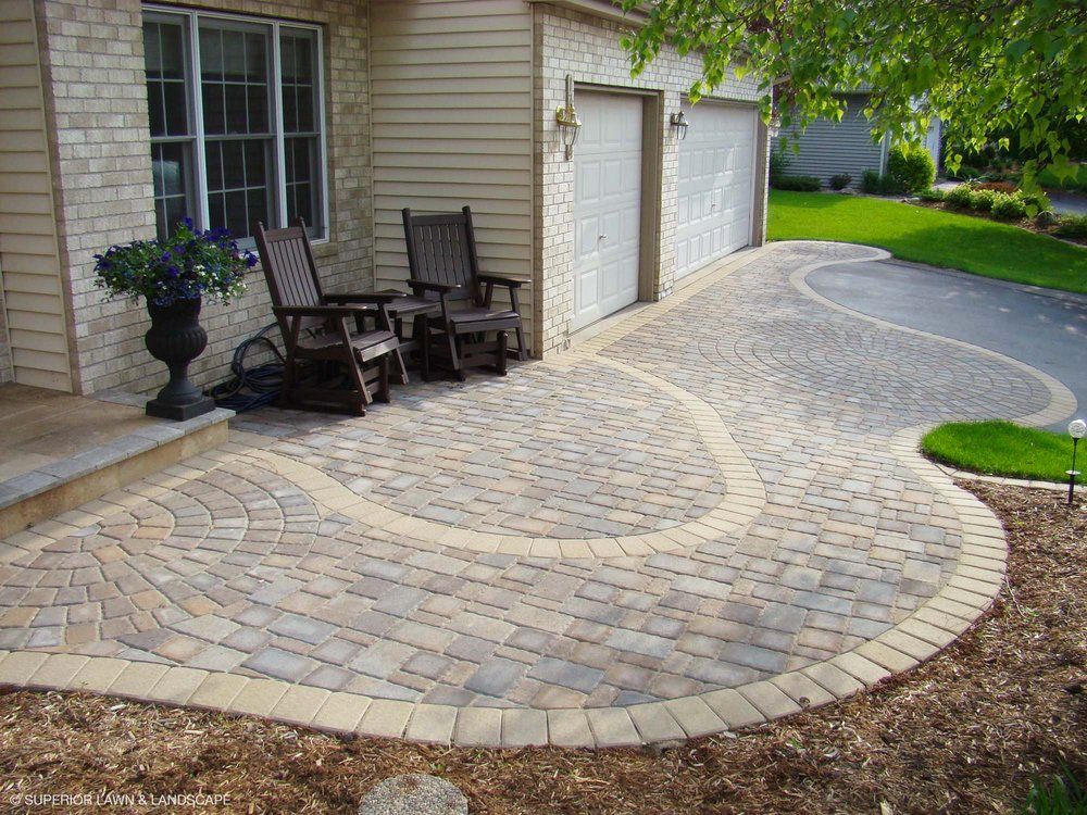 Two rocking chairs are sitting on a patio in front of a house.