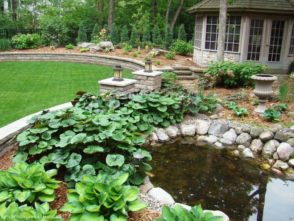 A garden with a pond and a gazebo in the background