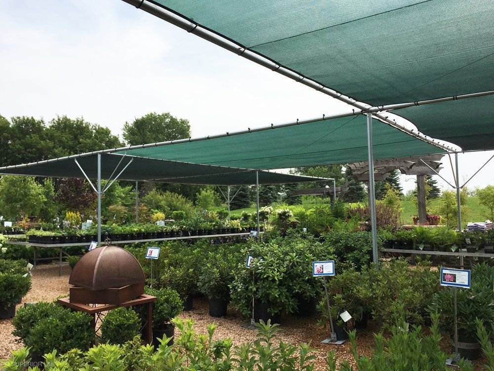 A garden with lots of potted plants under a green shade