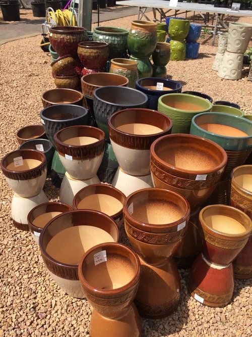 A bunch of pots are stacked on top of each other on gravel.