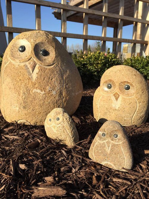Three rock owls are sitting on a pile of mulch