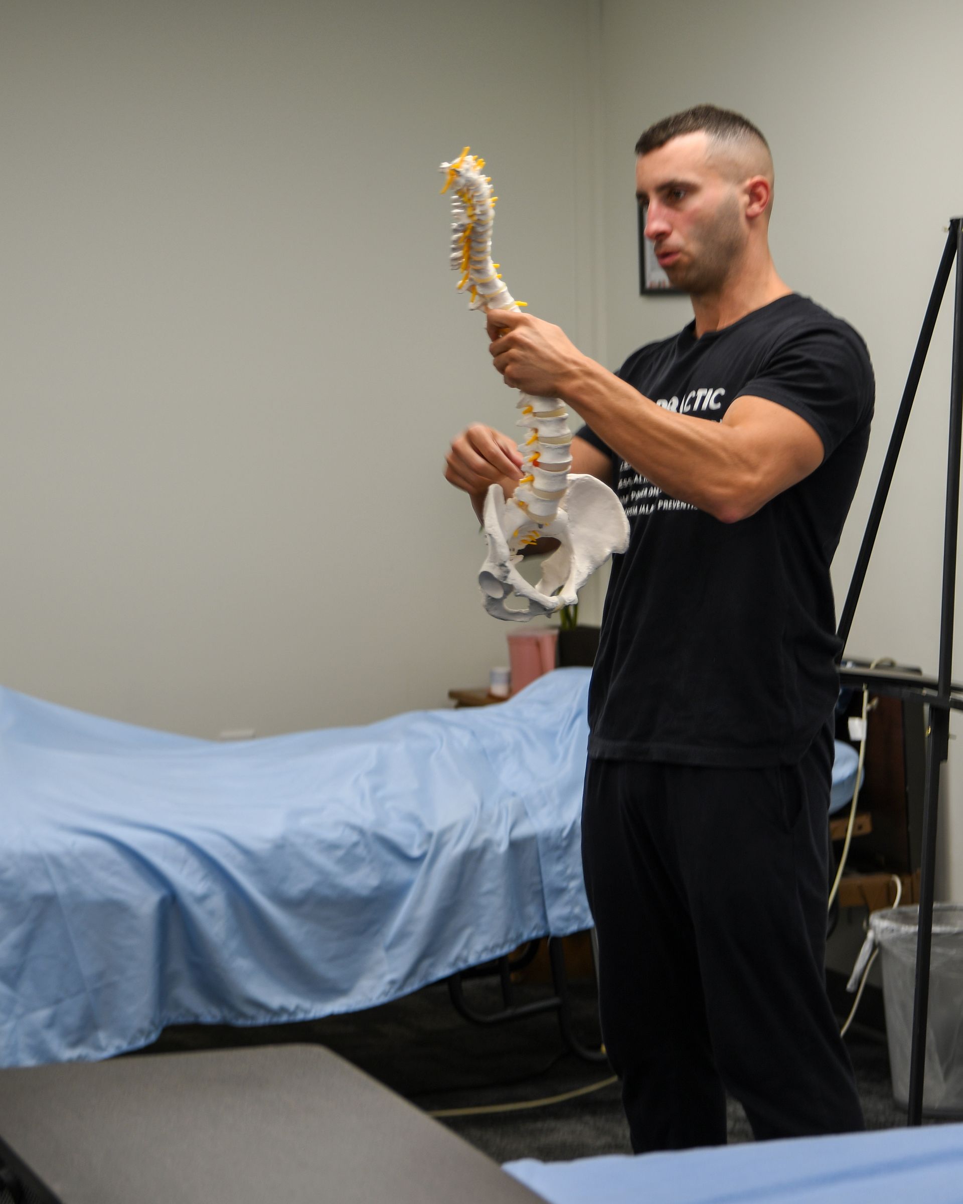 Man holding spinal column model, explaining its parts.