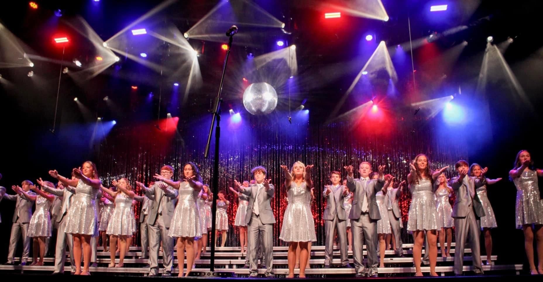 A group of people are standing on a stage in front of a disco ball.