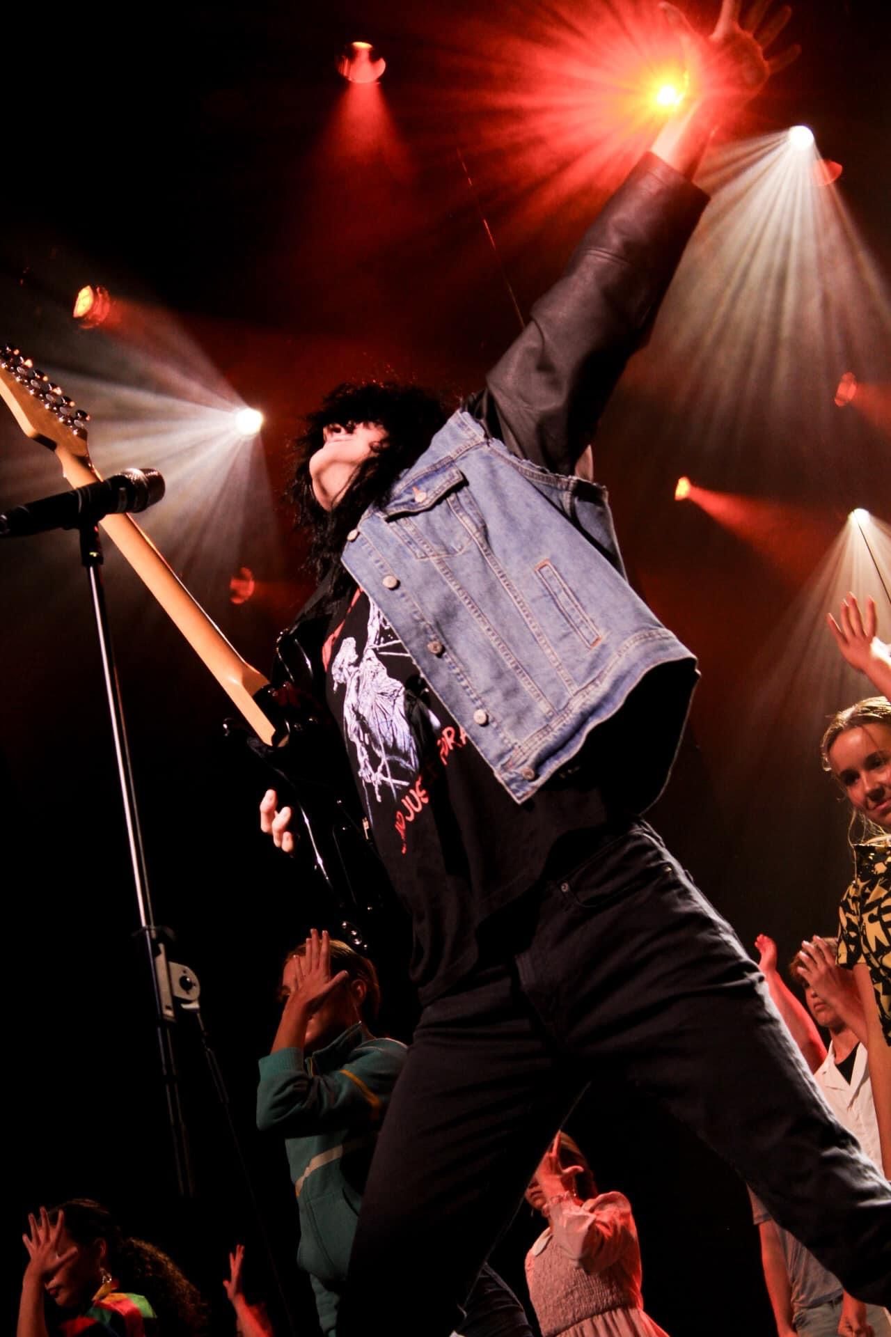 A man is playing a guitar on a stage in front of a crowd.