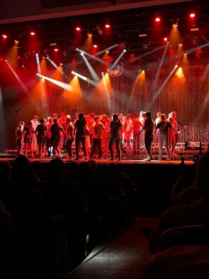 A group of people are standing on a stage in front of a crowd.