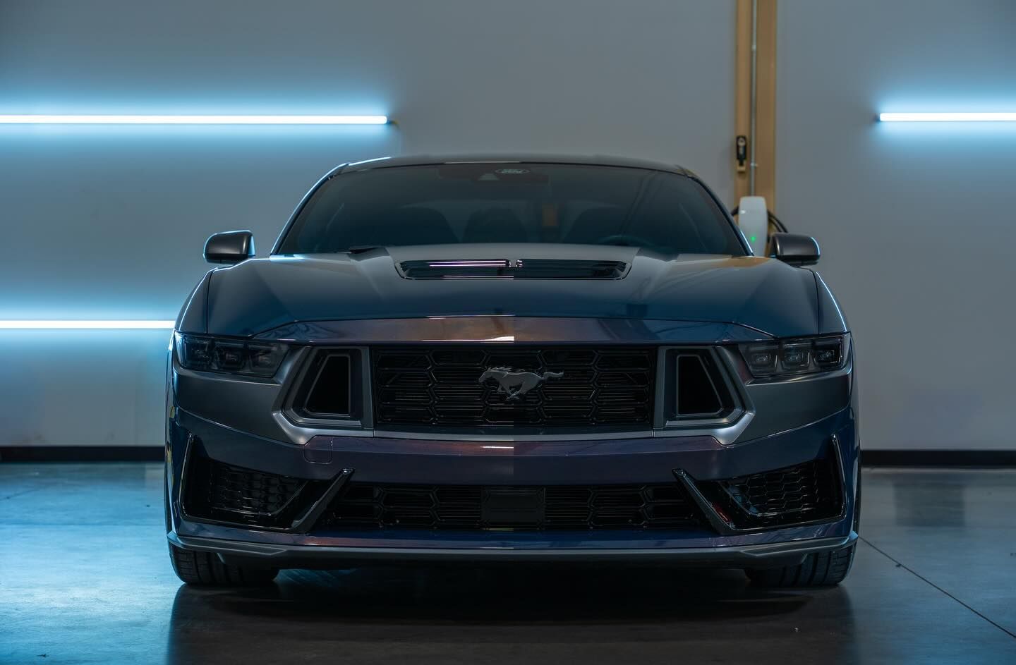 Front view of a black sports car in a garage with blue accent lights