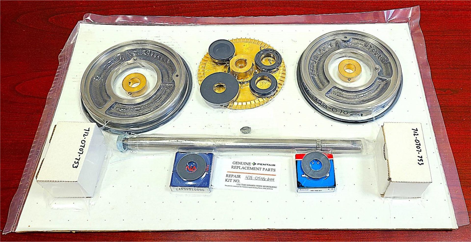 A tray of gears and a metal rod on a wooden table