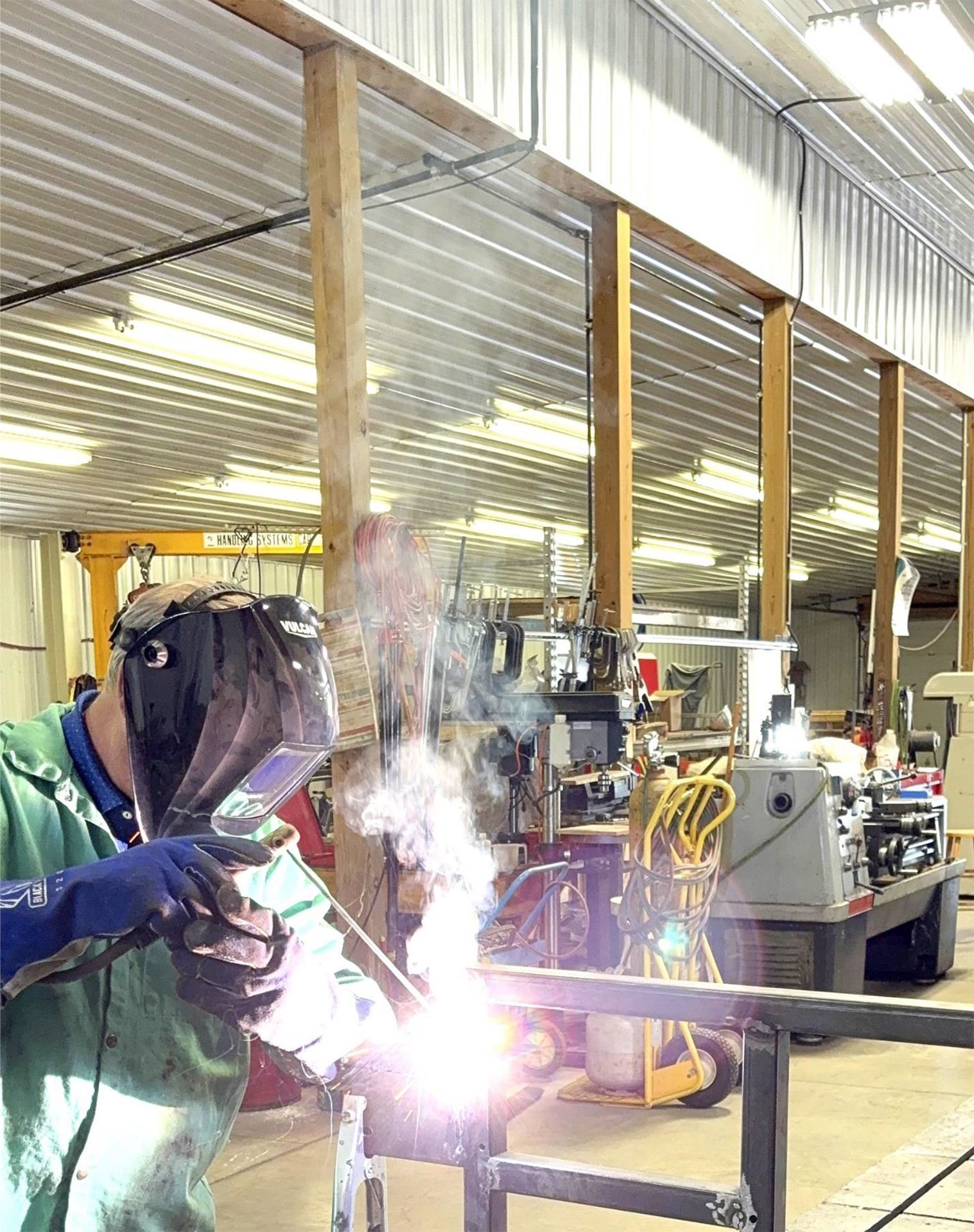 A man is welding a piece of metal in a factory