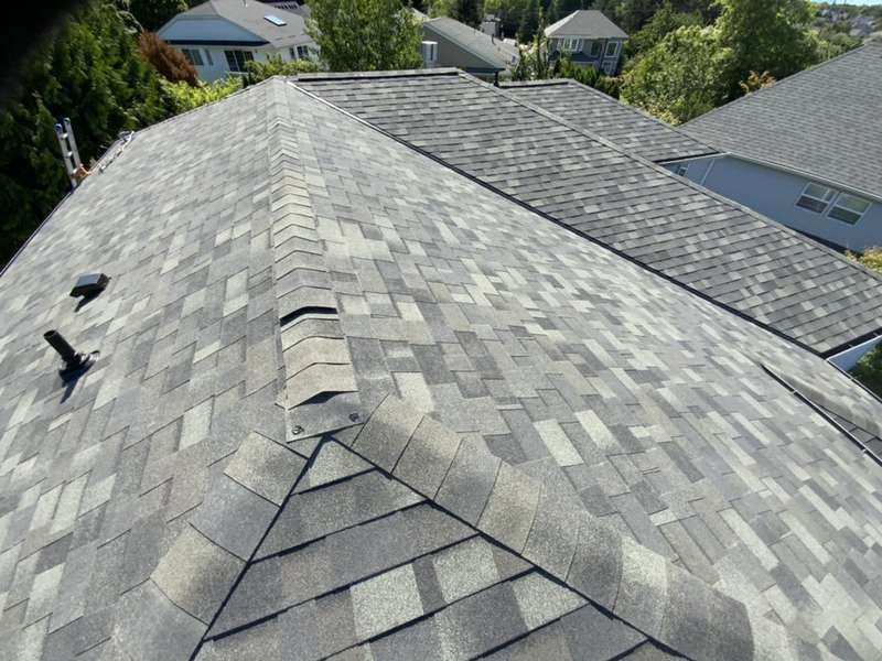 Gray asphalt shingle roof on a house, angled view, overcast day.