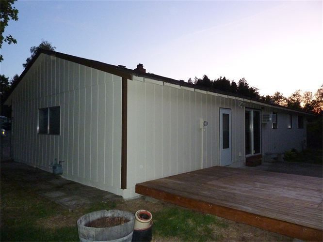 Beige house with brown trim and a wooden deck at dusk.