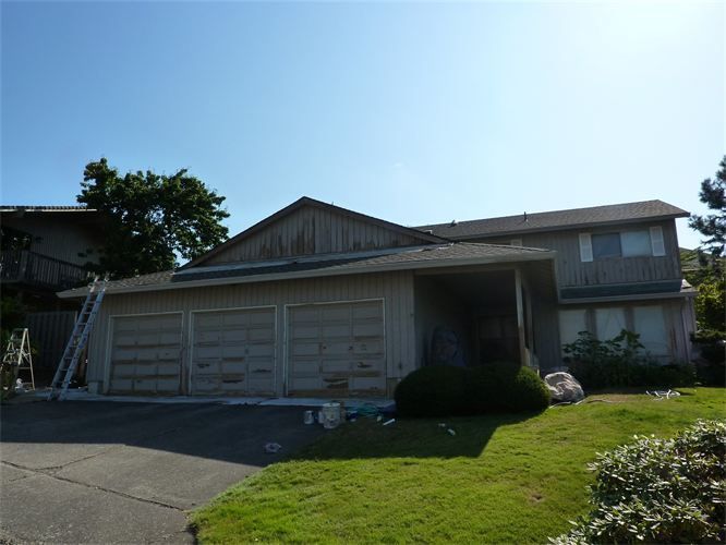 Two-story house with attached garage, driveway, and yard. Exterior needs paint. Ladders visible.