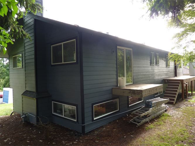 Dark blue house with rectangular windows, sliding glass door, and wooden deck.