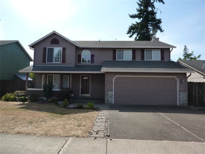 Two-story house with a gray garage, red siding, and a brown front door, set on a sunny day.
