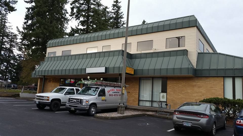 Exterior of a two-story building with a brick facade and vehicles parked outside.