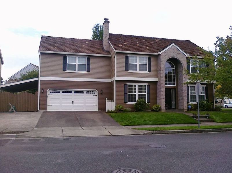 Two-story house with brown siding, white garage door, and a brick entryway.