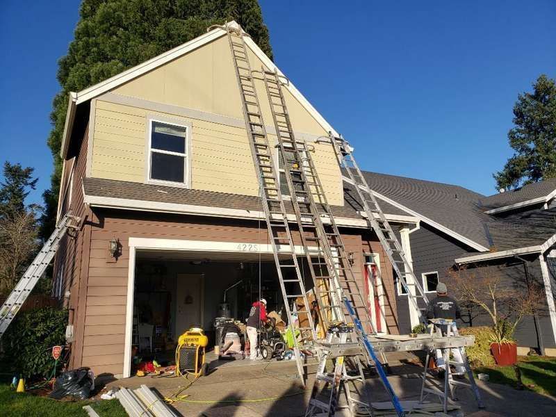 House exterior with multiple ladders against siding; construction in progress.