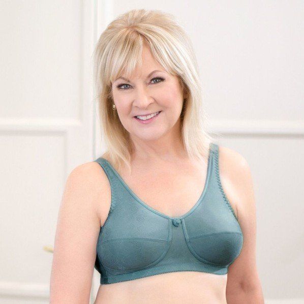 A woman is wearing a green bra and smiling.