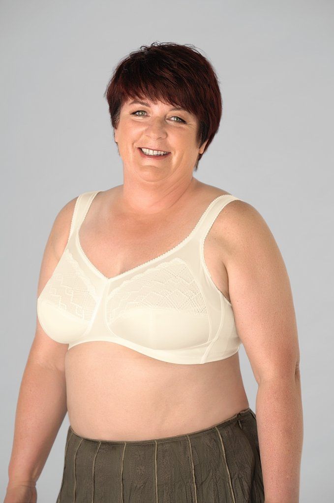 A woman wearing a white bra and a brown skirt is smiling.
