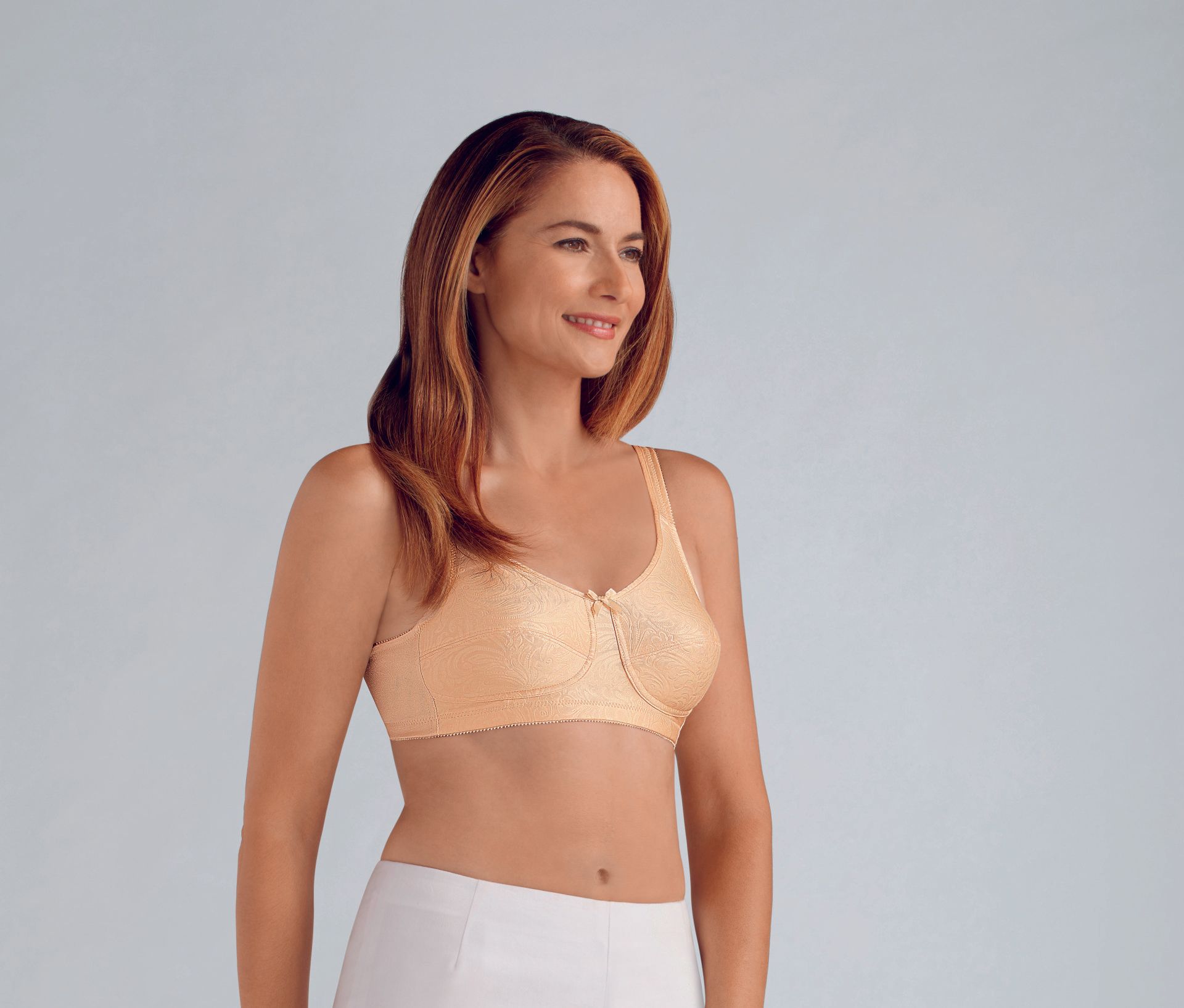 A woman is wearing a bra and white pants.