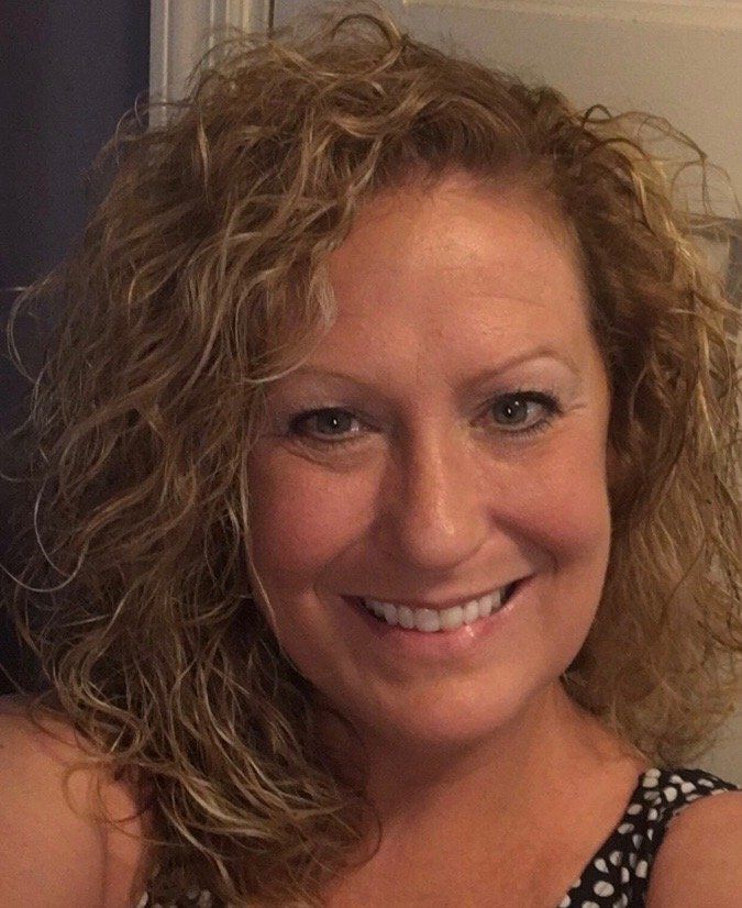 A woman with curly hair is smiling for the camera.