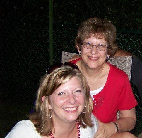 Two women are posing for a picture and one is wearing glasses