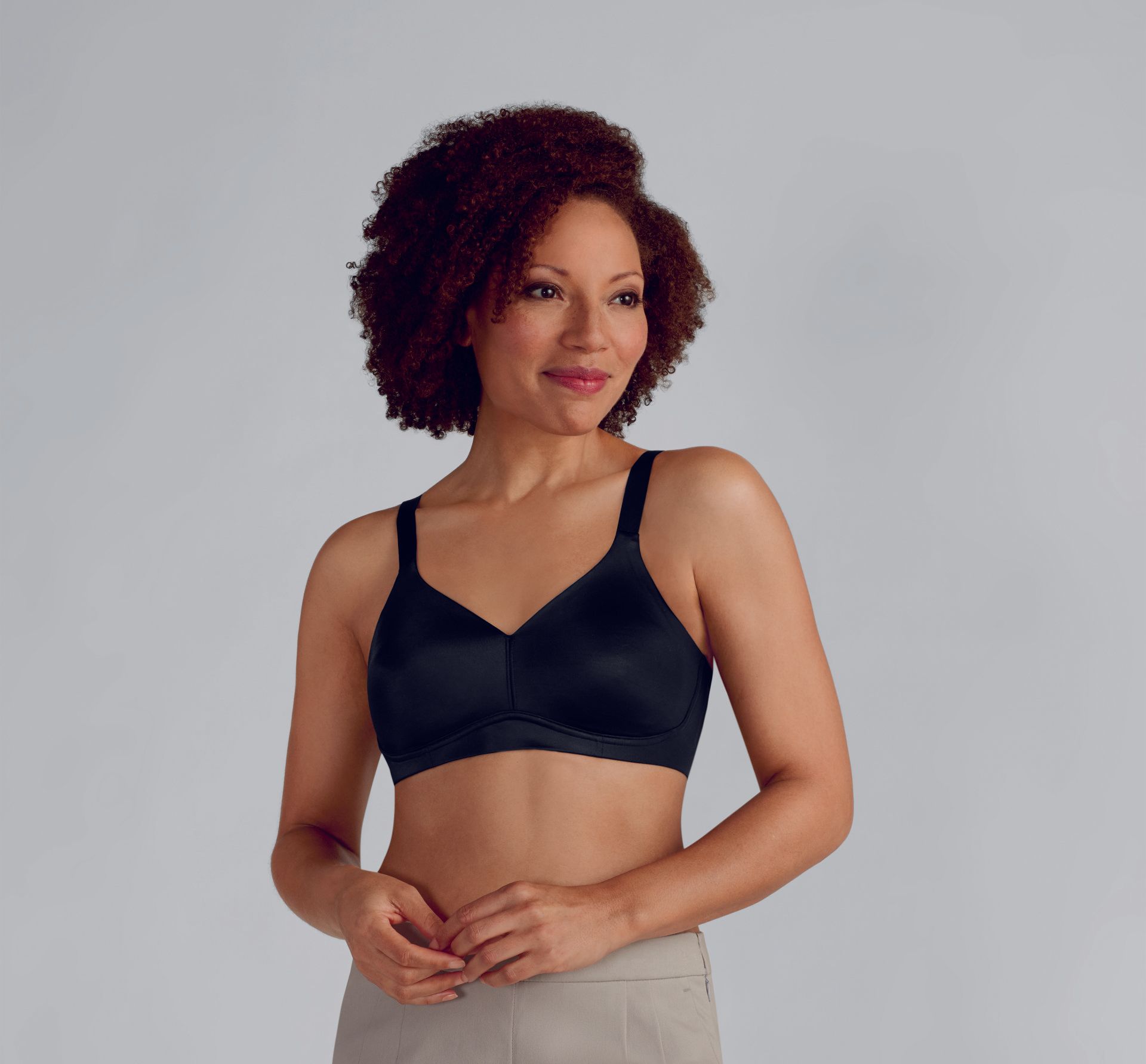 A woman is wearing a black bra and khaki pants.