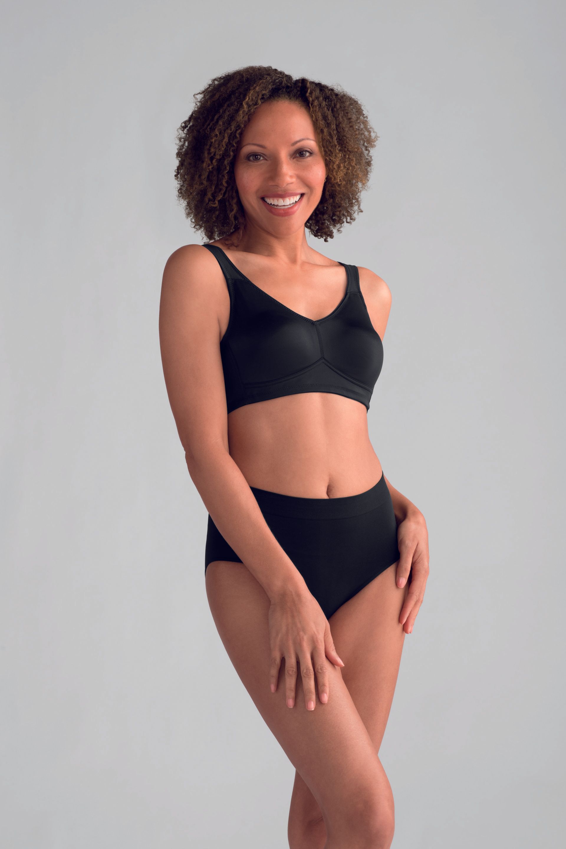 A woman is wearing a black bra and panties and smiling.