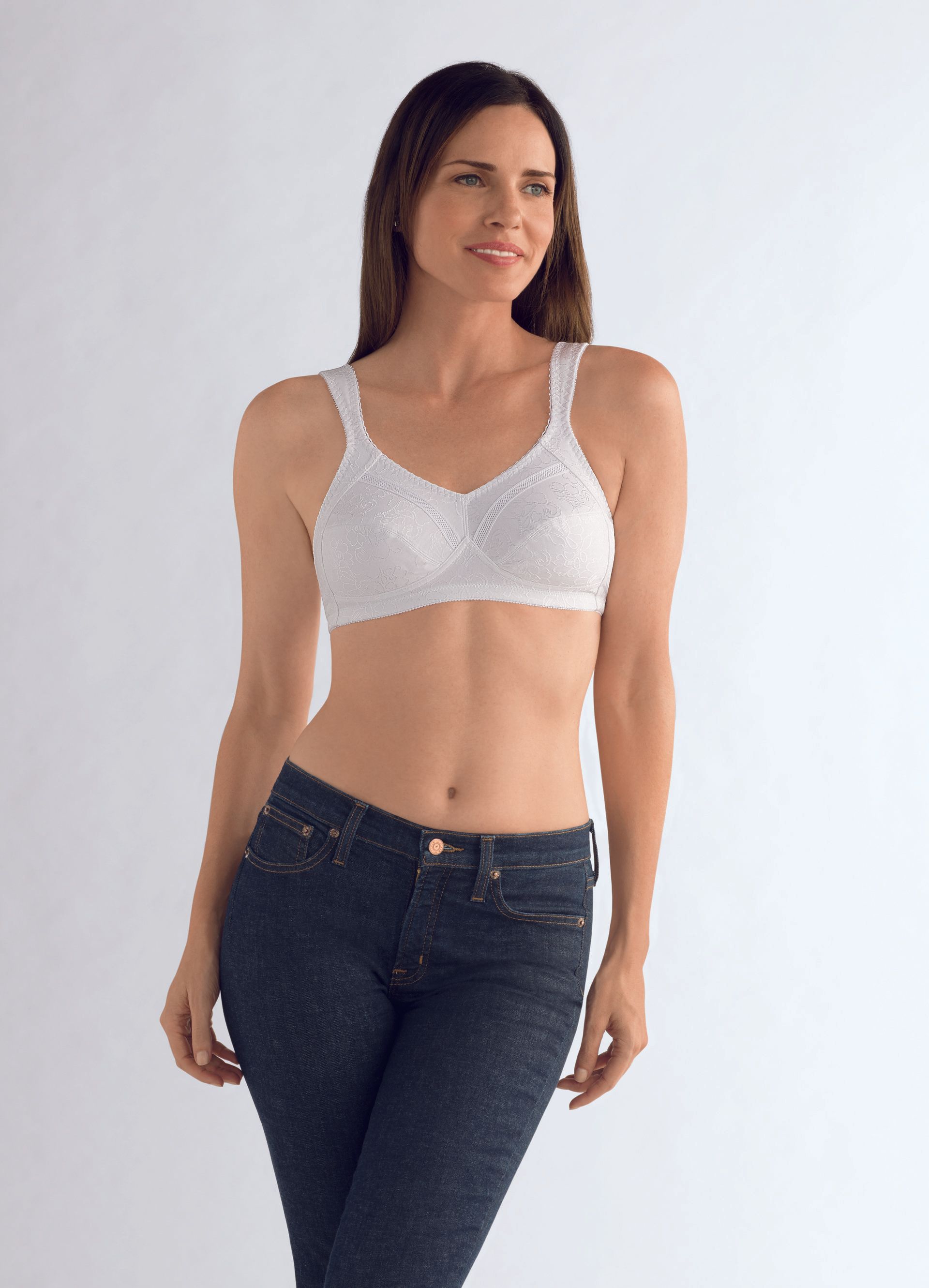 A woman is wearing a white bra and blue jeans.