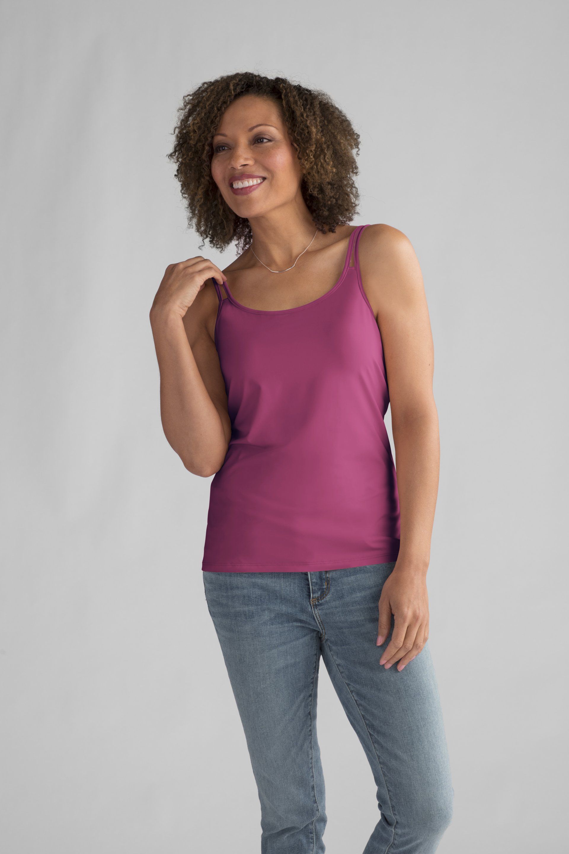 A woman is wearing a purple tank top and blue jeans.