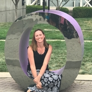 A woman is sitting in a purple circle sculpture.
