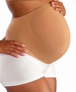 A pregnant woman is wearing a brown belly band and white shorts.