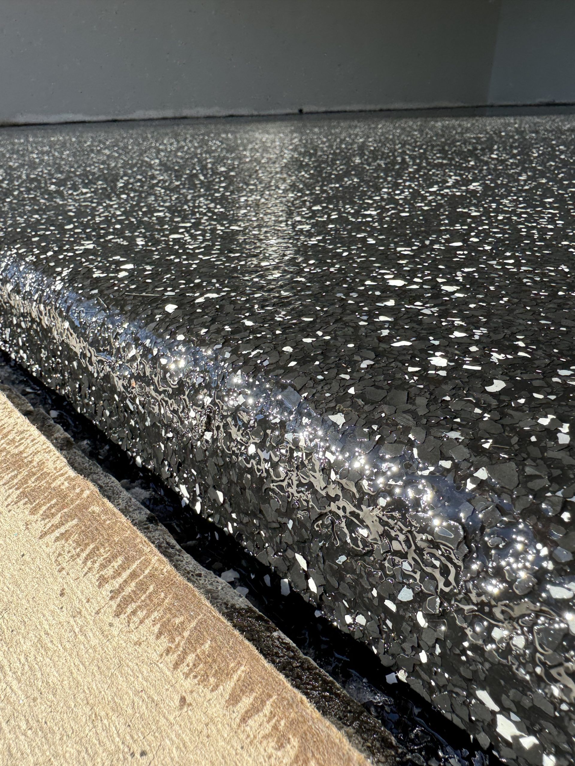 Black speckled stone countertop edge with beige surface below
