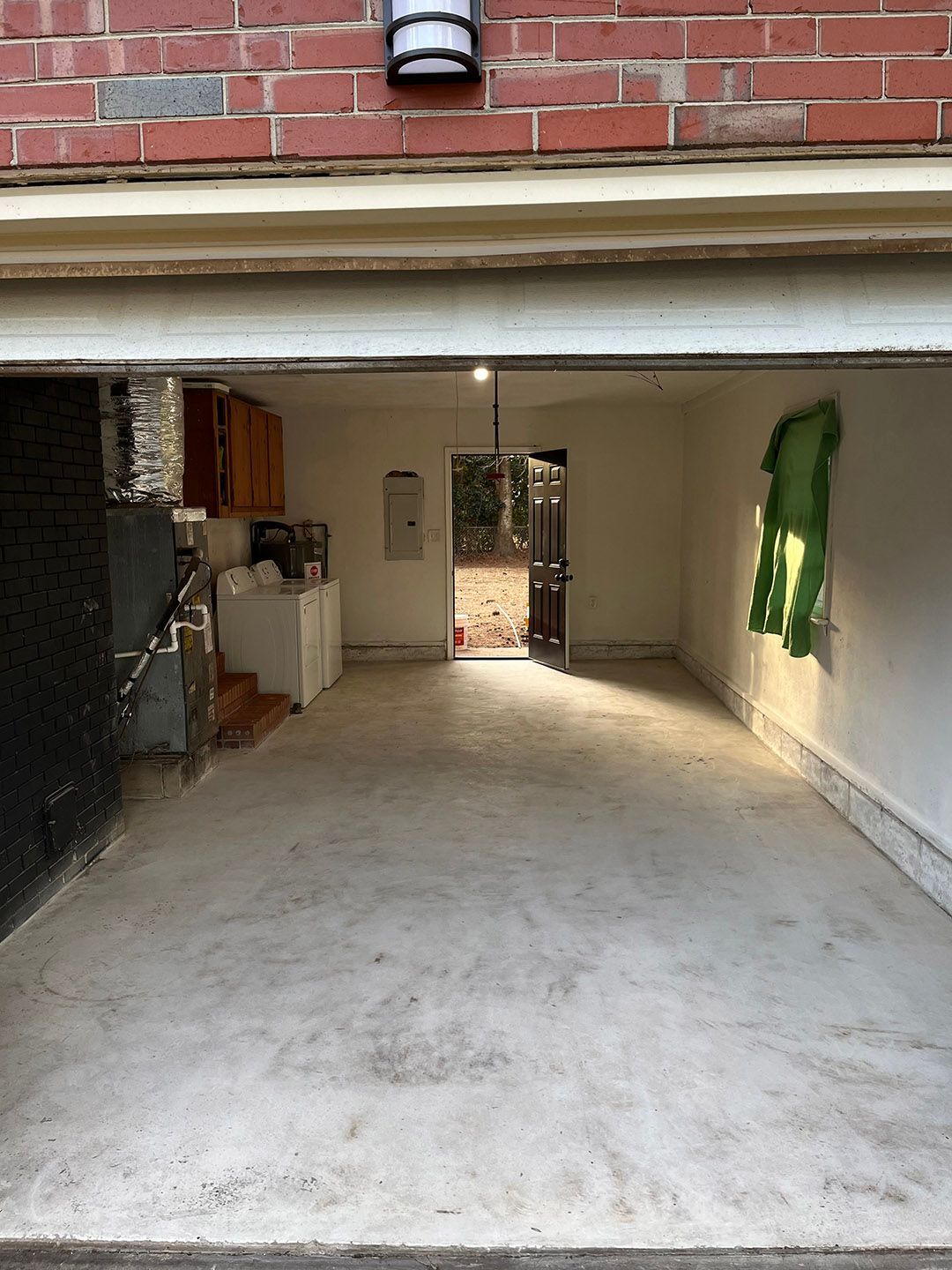Empty garage with concrete floor, brick wall, and an open doorway to a courtyard.