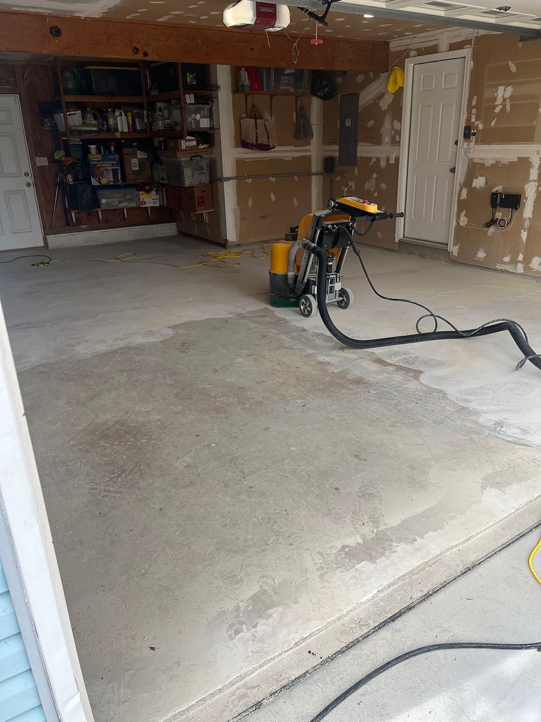 Partially finished garage with drywall, shelves, and a flooring machine on the concrete floor