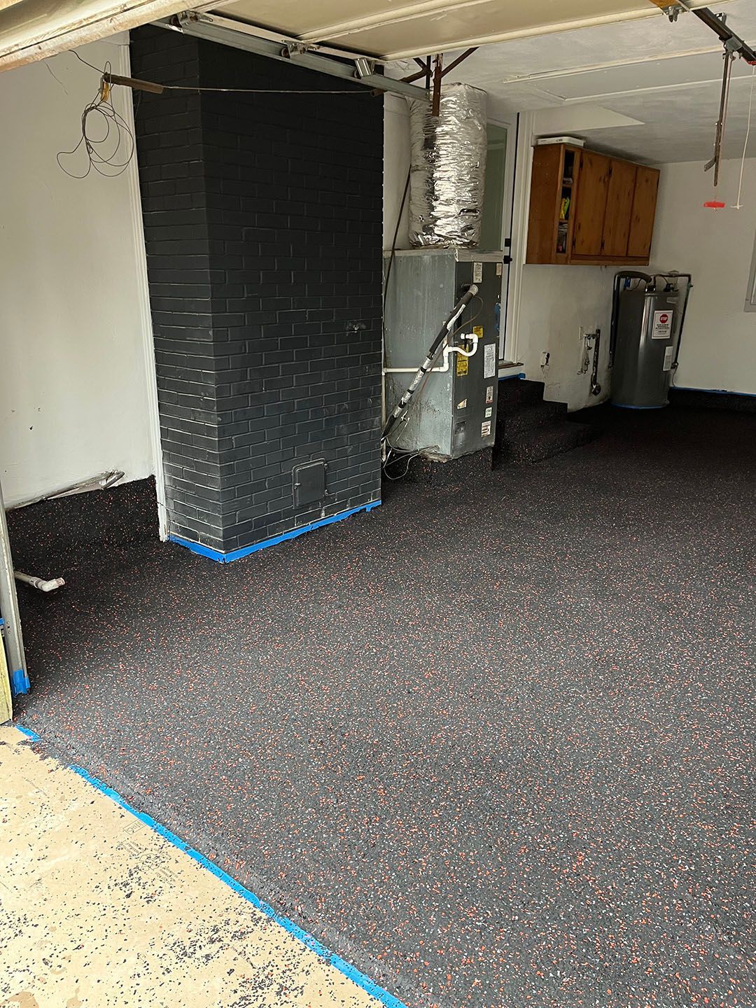 Garage interior with black flooring, exposed ceiling, and a utility area at the back.