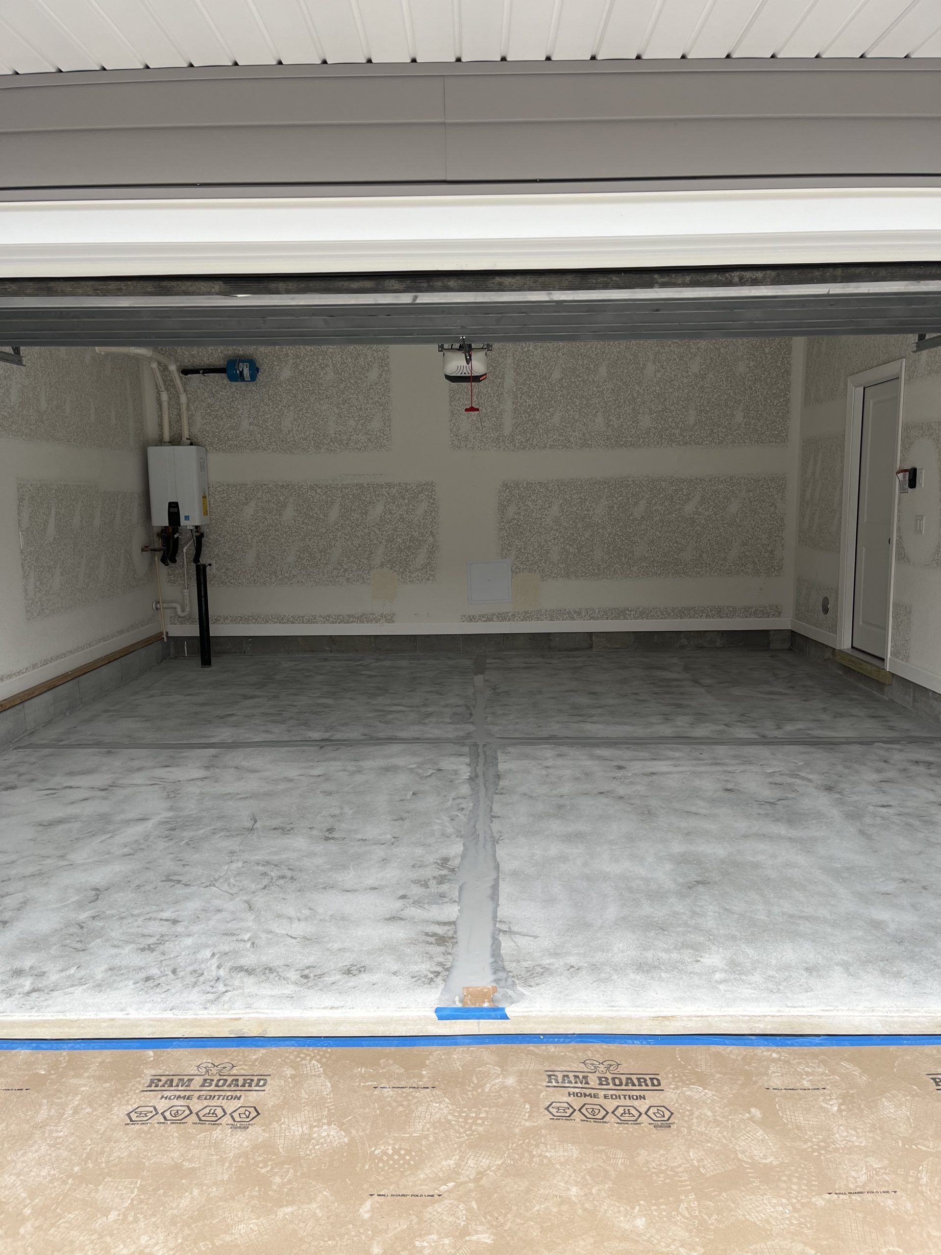 Empty concrete garage interior with closed white door and painted floor lines
