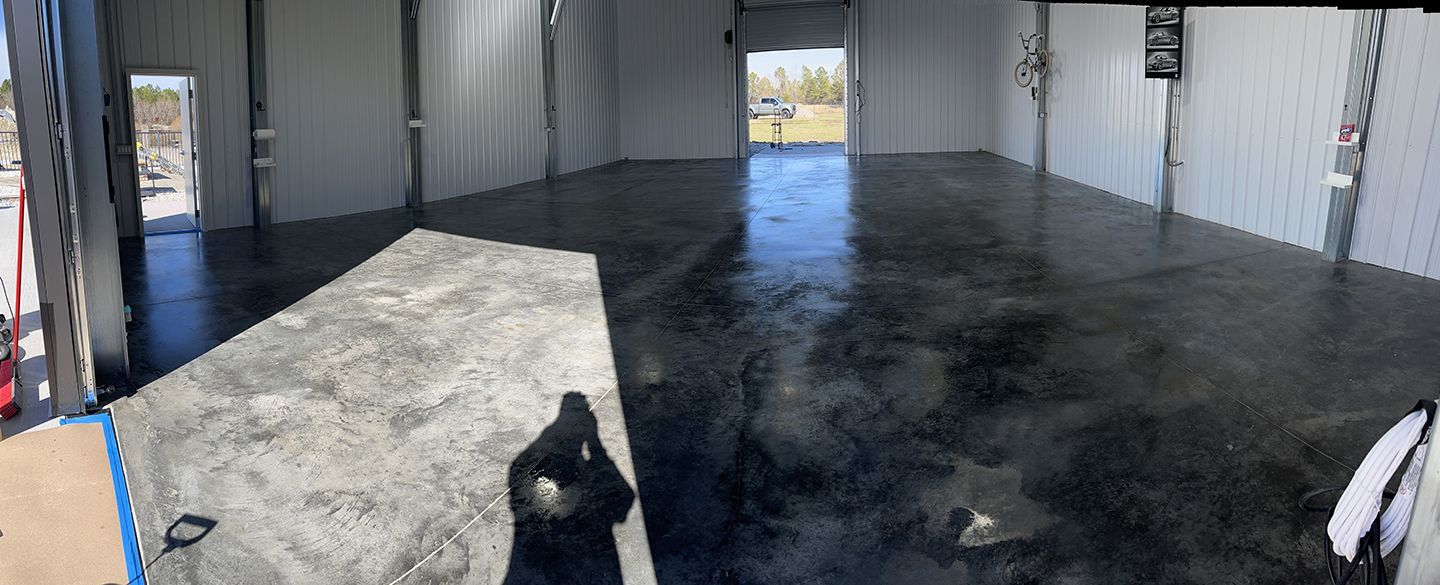 Empty warehouse interior with a concrete floor, open bay doors, and a small white partition on the left