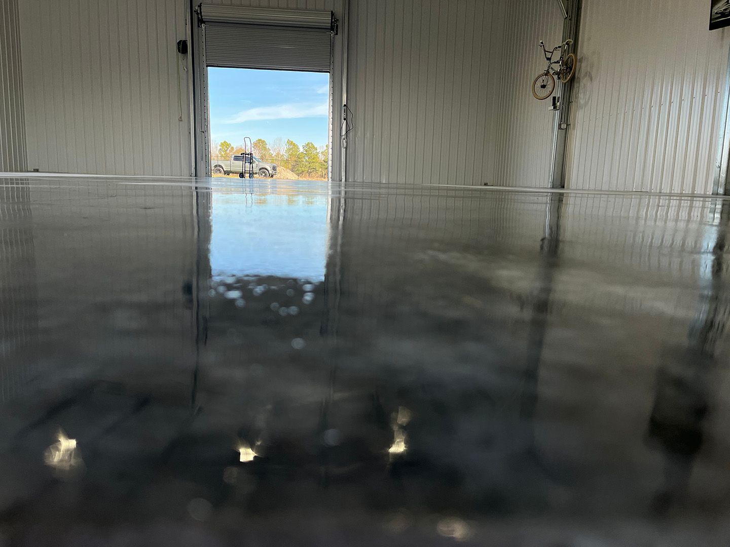 Empty indoor pool with reflective dark water and a doorway opening to a bright outdoor view.