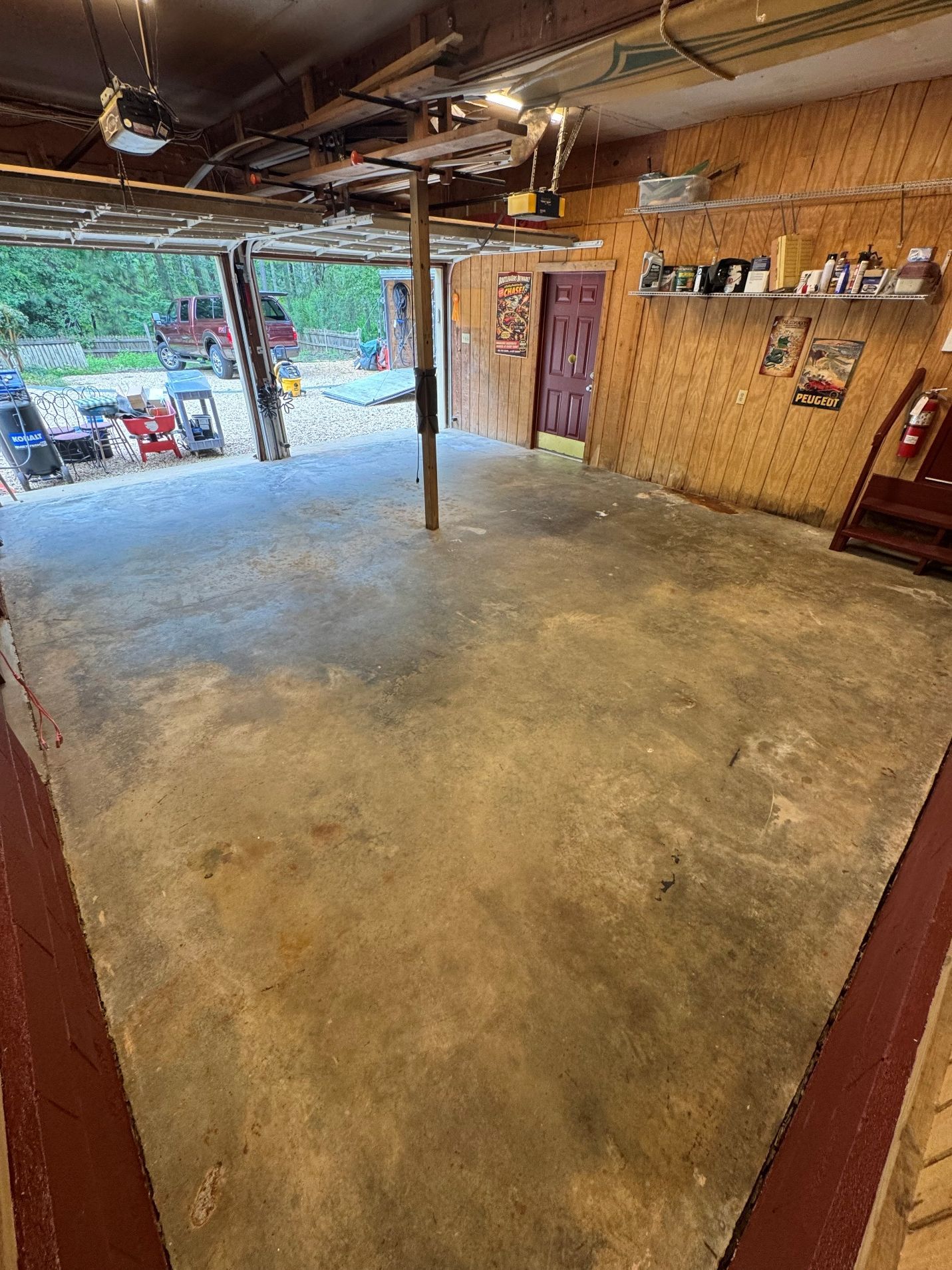 Empty unfinished room with concrete floor, exposed beams, and a wooden door near the entrance.
