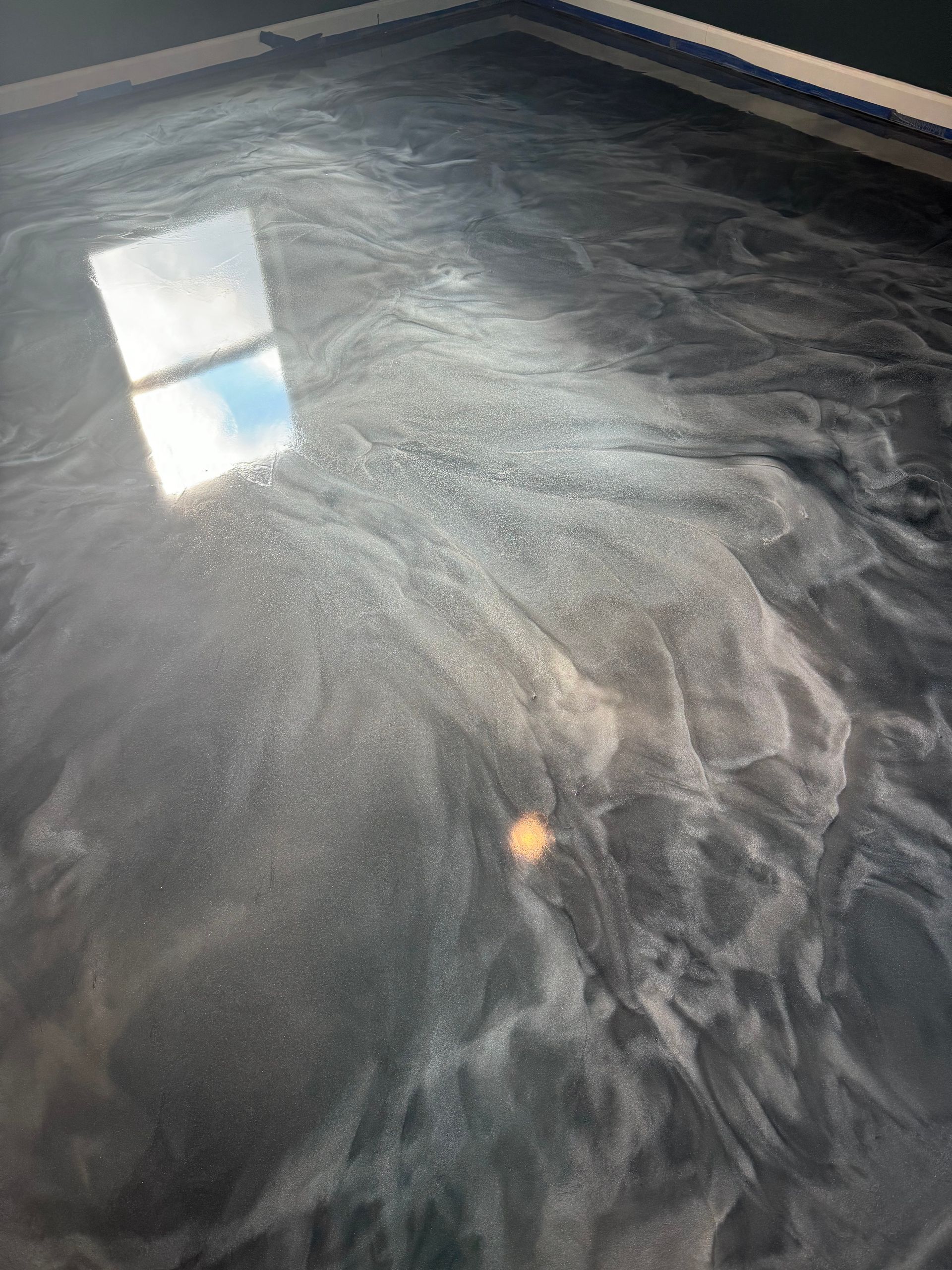 Reflective dark water with swirling ripples and a bright window reflection on the surface