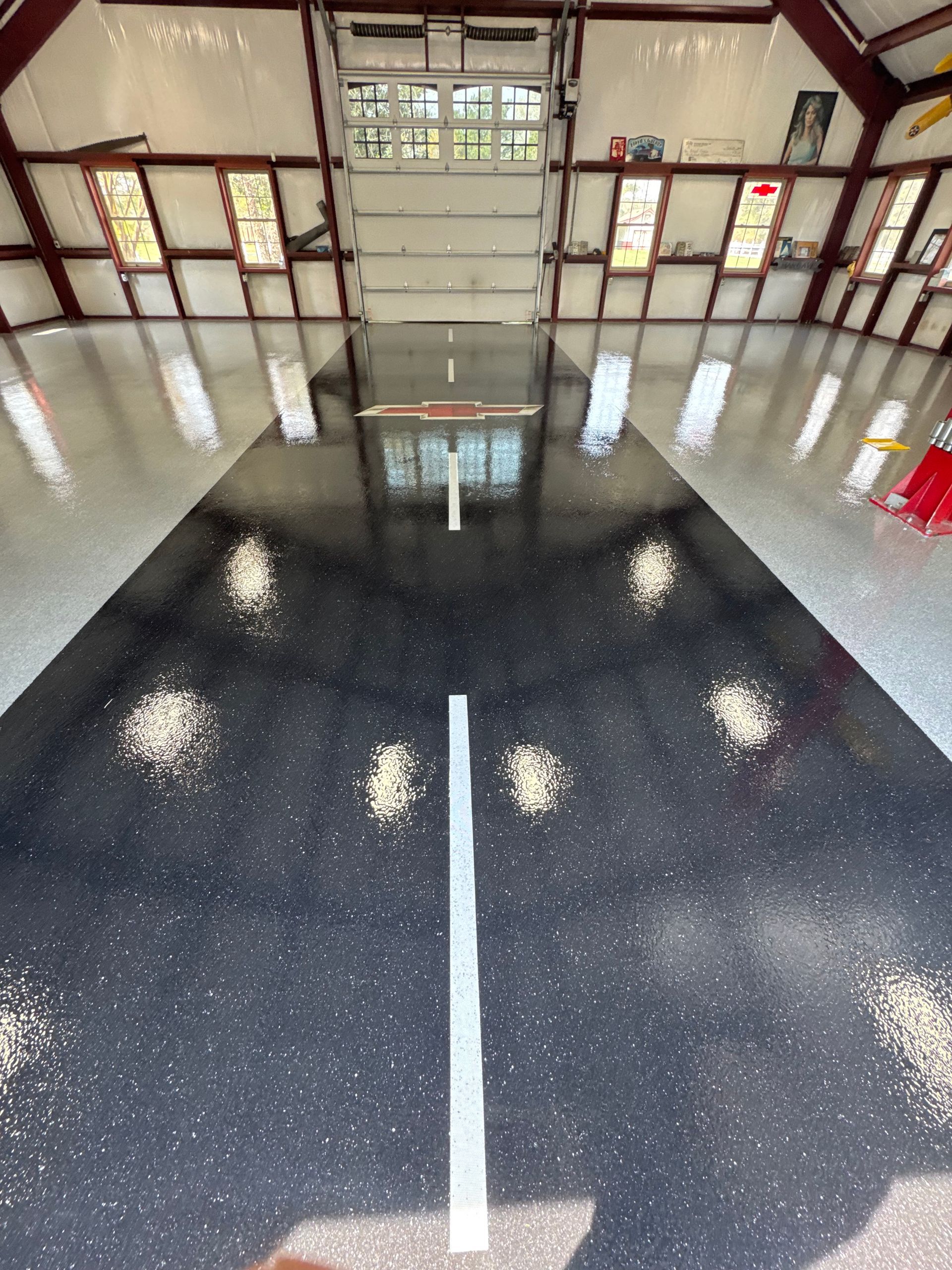 Empty indoor basketball court with glossy black floor and white center line, seen from mid-court.