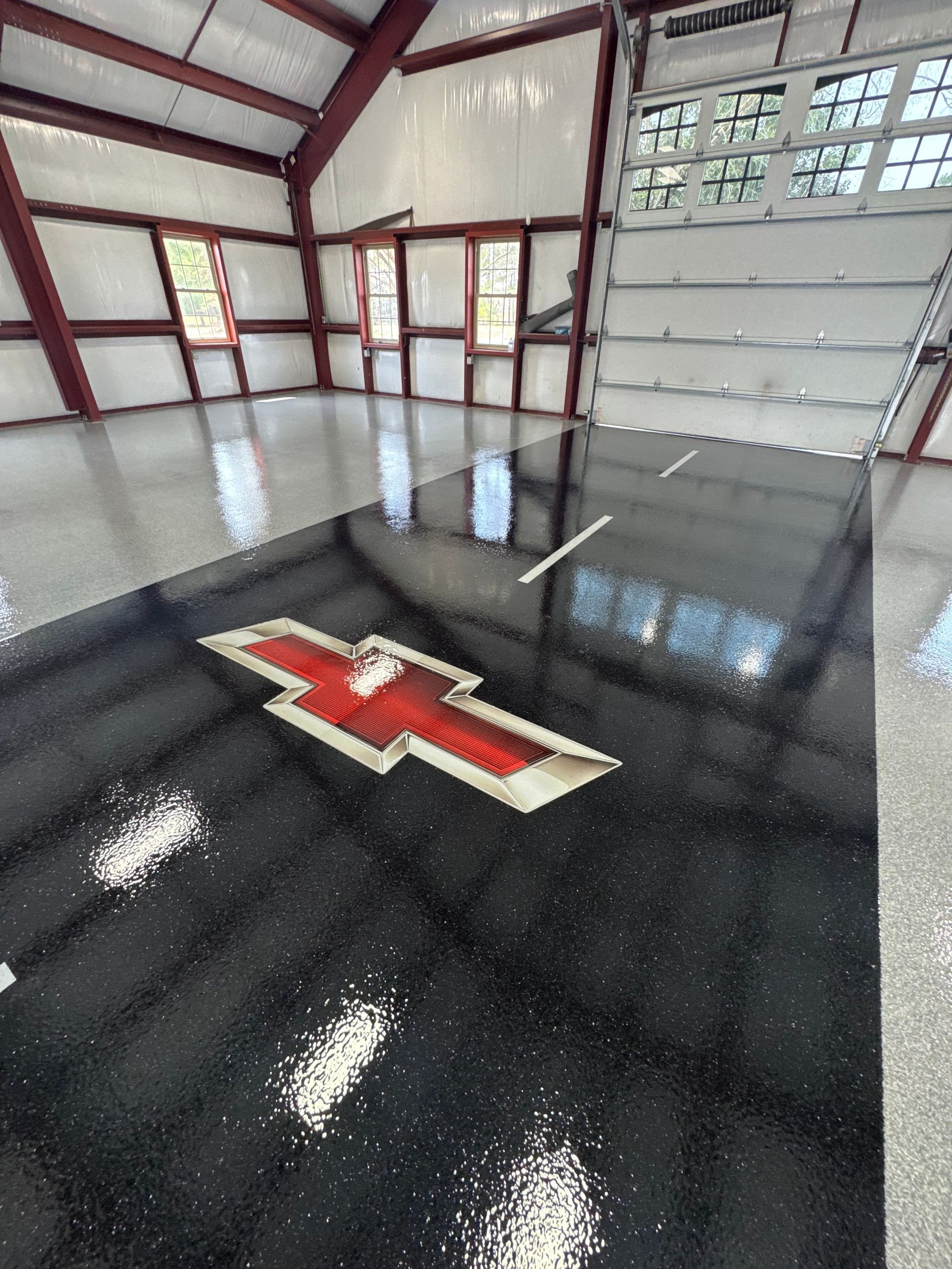Empty garage interior with glossy black floor and a red-and-white emblem near the center.