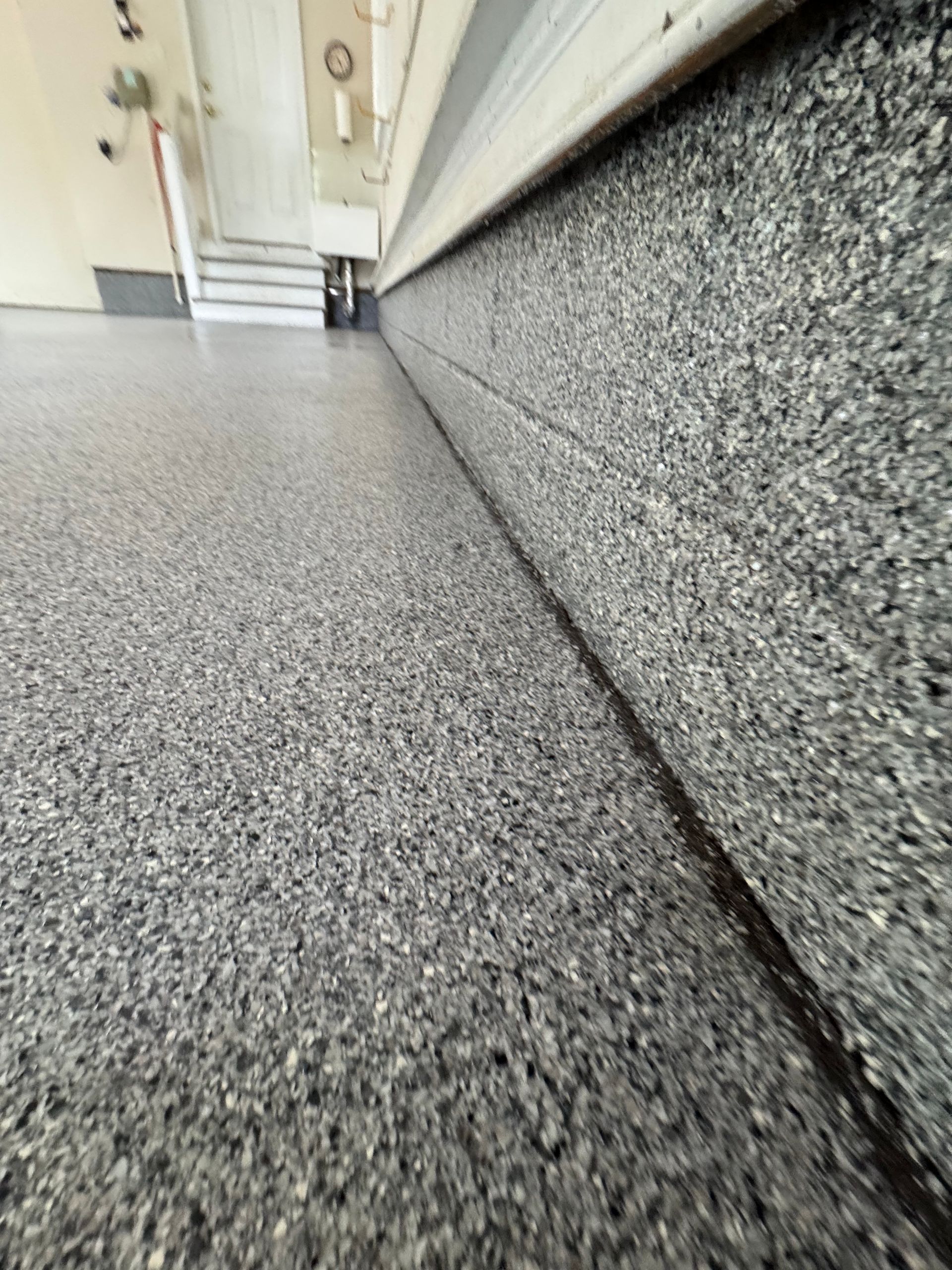Low-angle view of a carpeted hallway with gray textured walls and a white ceiling.