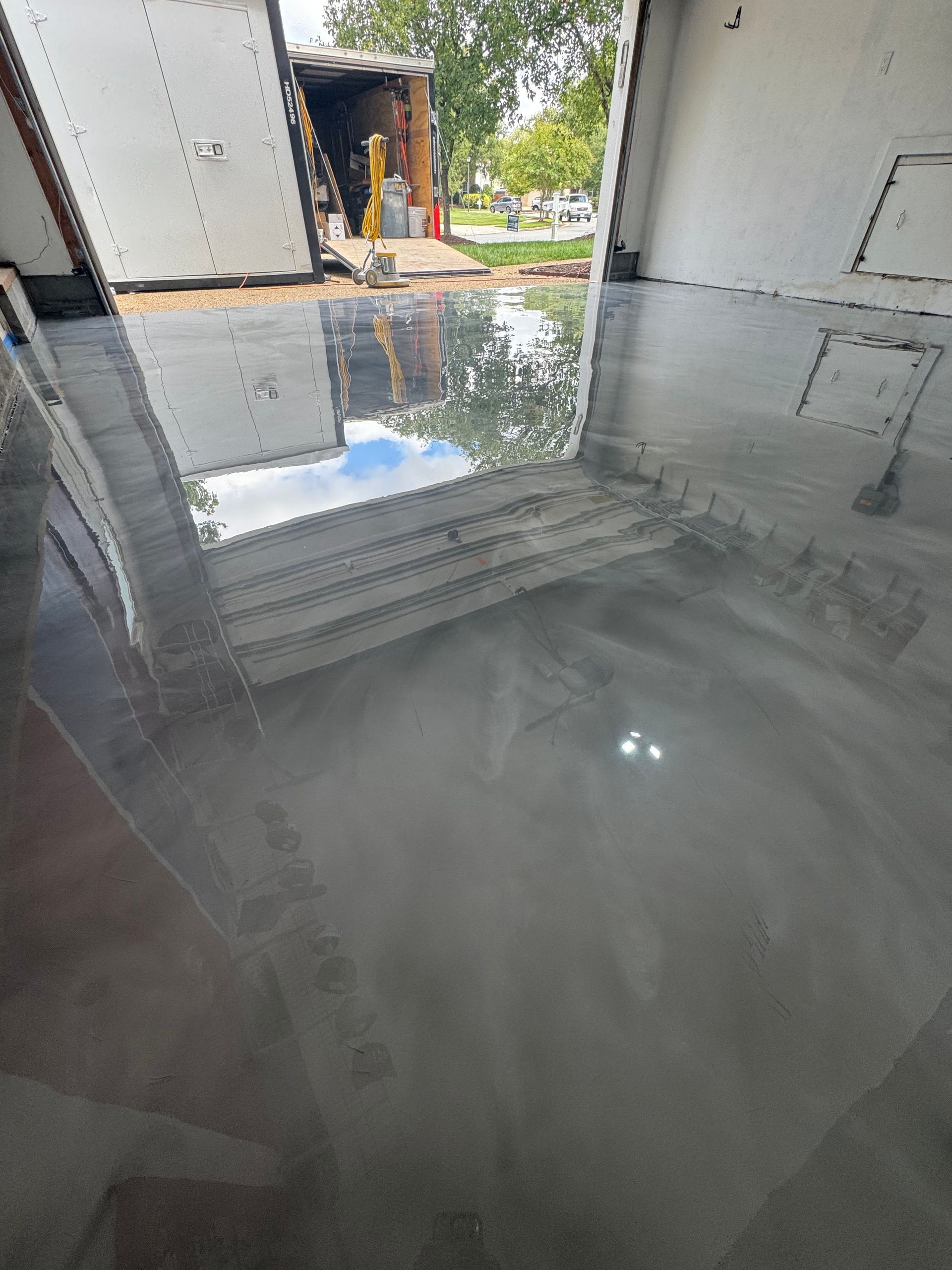 Flooded garage interior with reflective standing water and an open doorway to daylight.