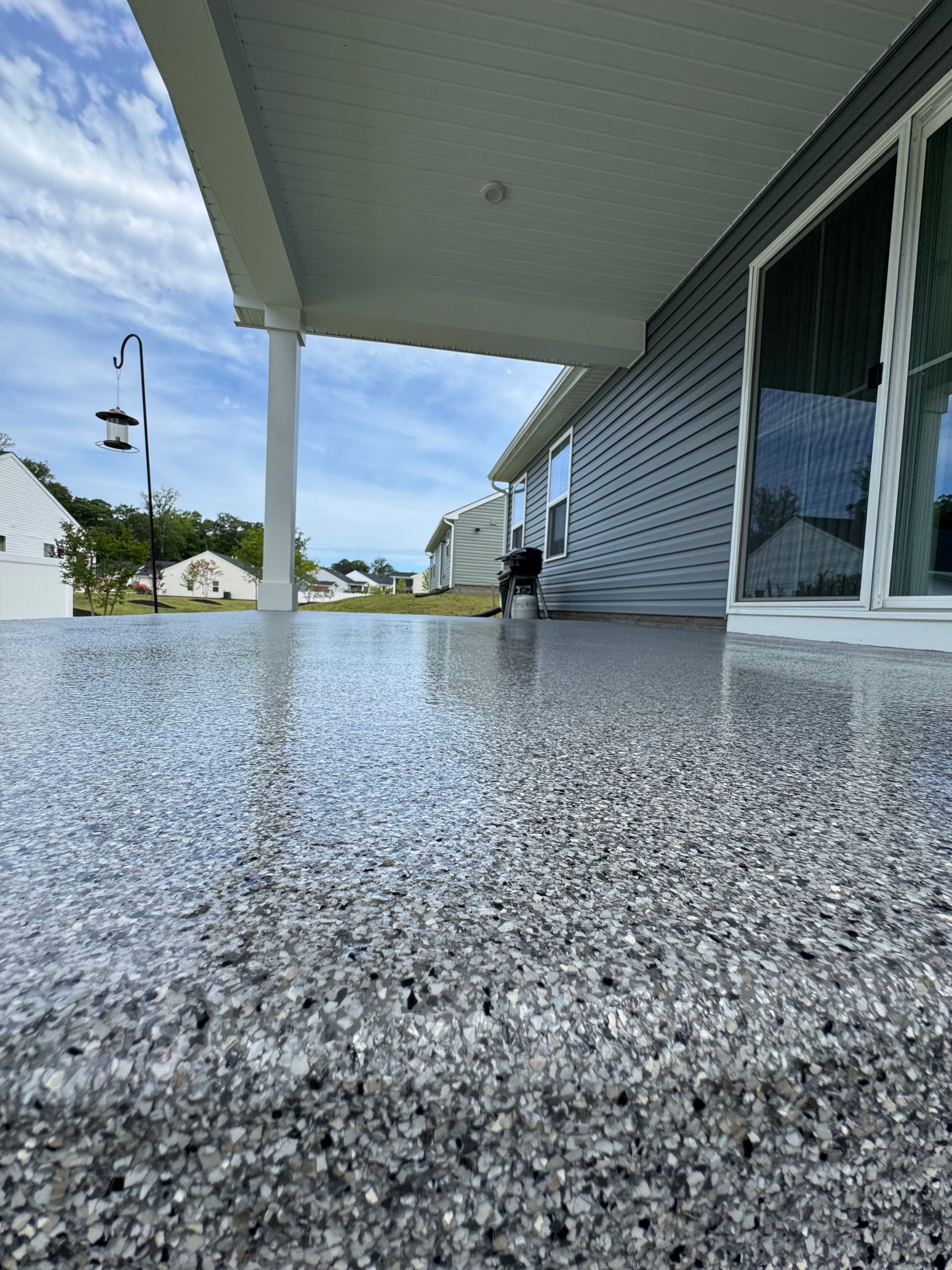 Wet speckled porch beside a house, with a person in the distance under an overhang.