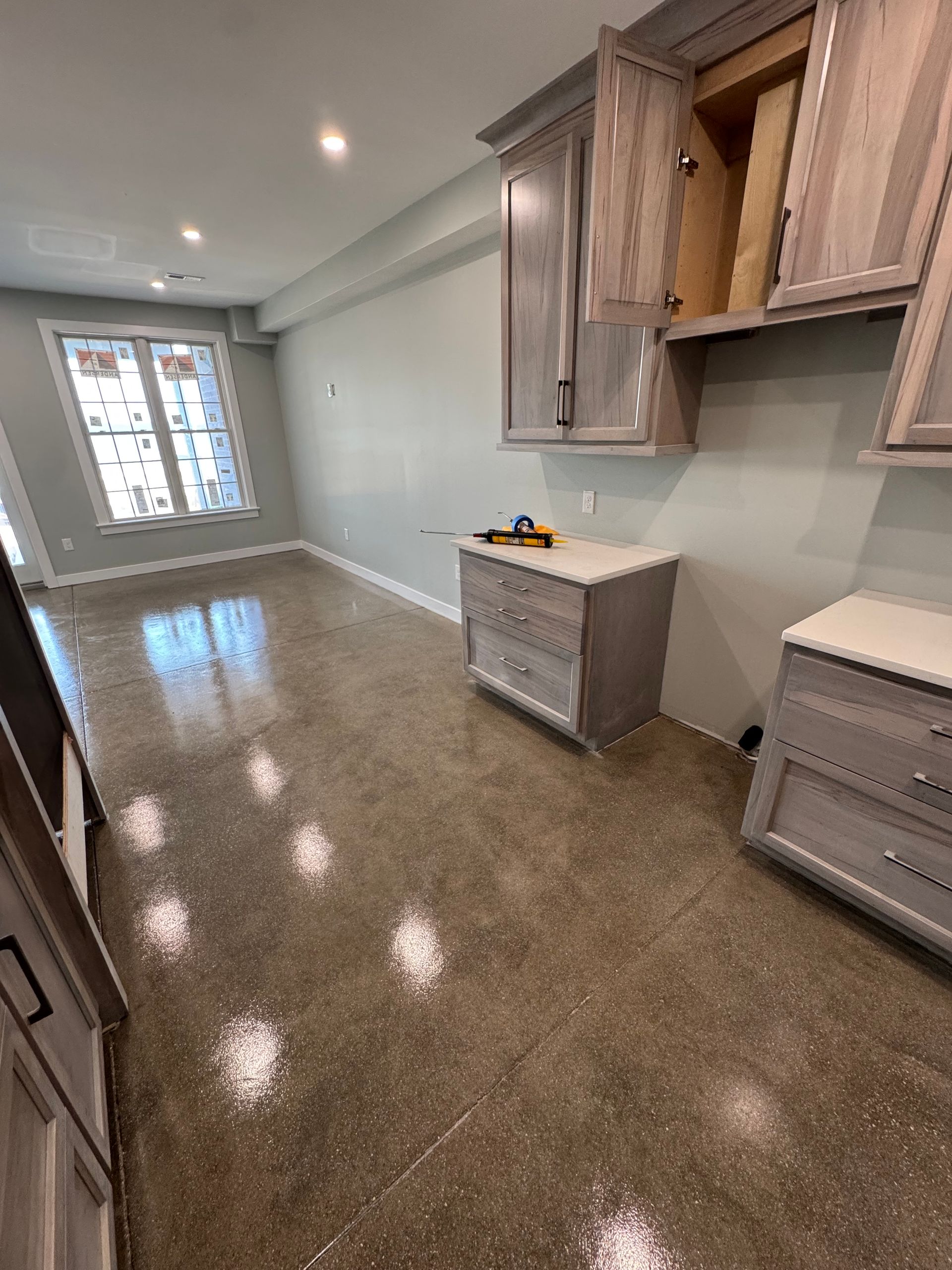 Empty modern room with glossy brown floor, light gray walls, and built-in cabinets along one side.