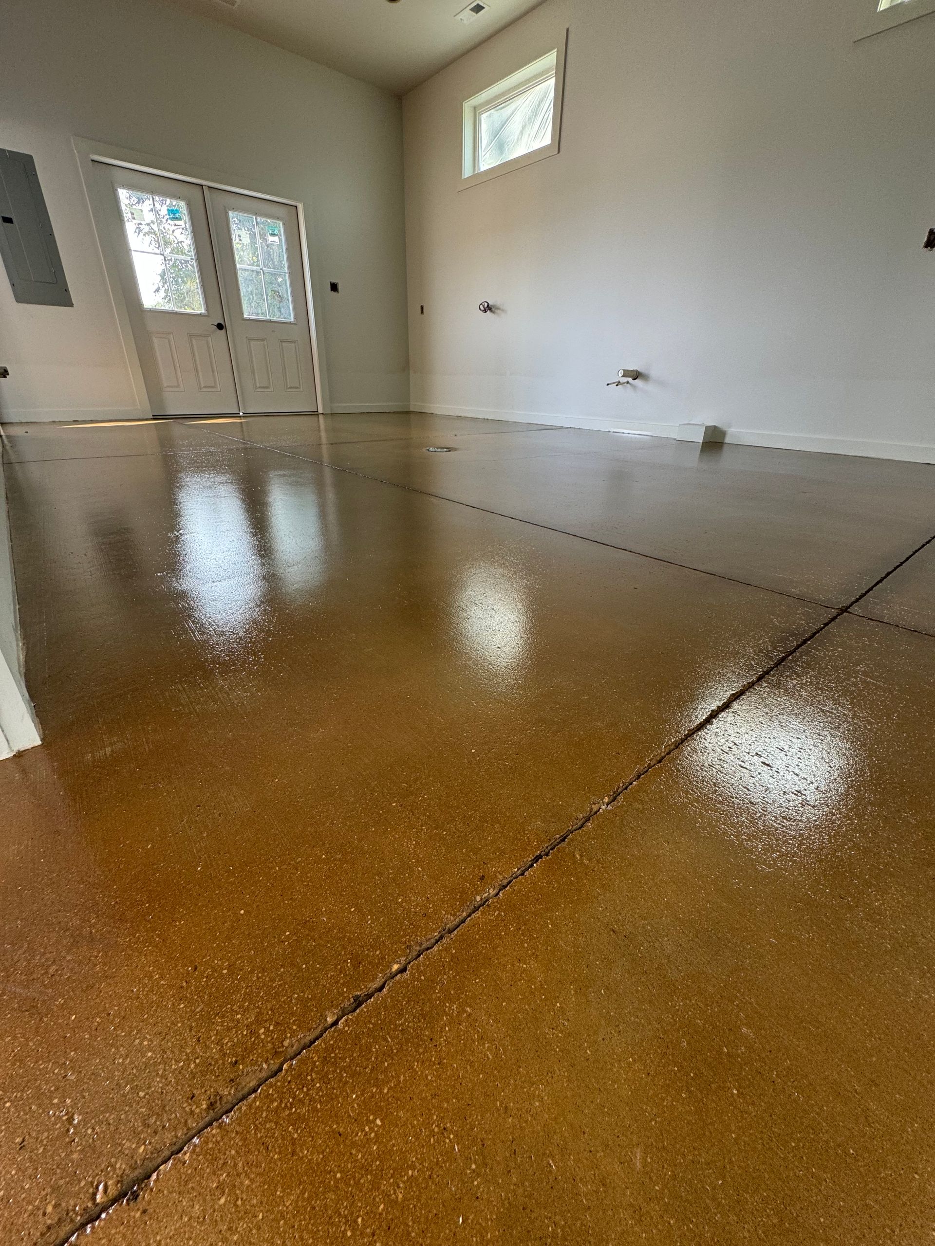 Empty room with glossy brown floor, white walls, and double doors with a small window.