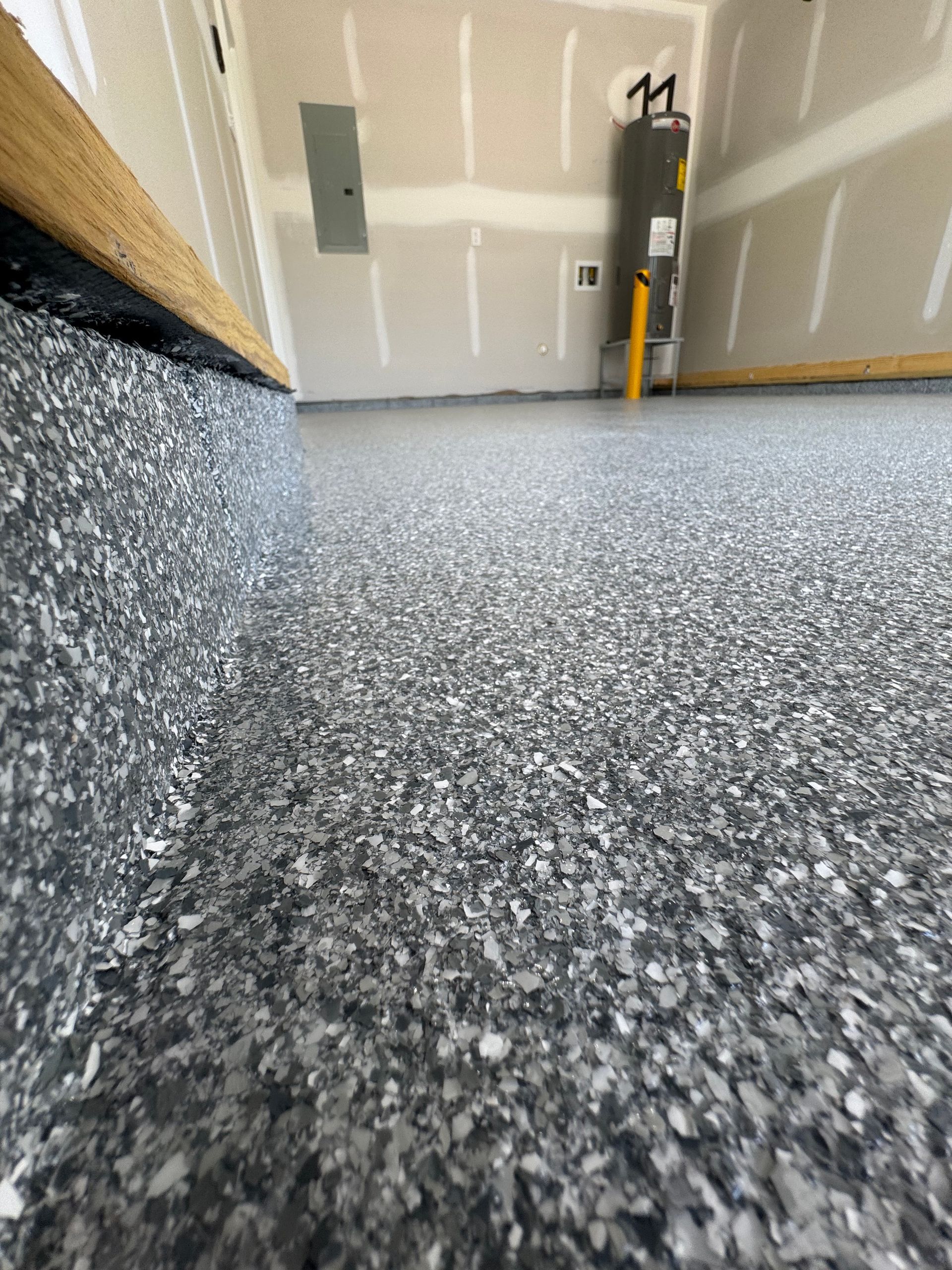 Garage floor with speckled epoxy coating, wall panels, and a ladder near the back wall